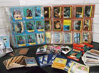 Photo showing sleeves filled with The A-Team cards, stacks of Star Wars cards, Yu-Gi-Oh! cards, and other miscellaneous trading cards laid out on a dark surface.