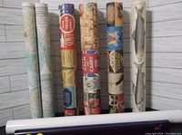 Rolled set of multiple posters with visible fish, world map, Paris, and other designs.