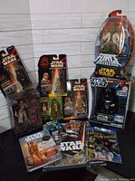 Wide view of Star Wars action figures and books arranged on the floor showing various sealed figures, books, and period collectibles