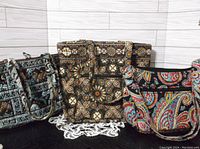 Three Vera Bradley quilted fabric bags sitting side by side showing different patterns and shapes