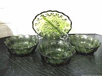 Full view of the vintage green glass relish dish and three matching bowls showing the thumbprint texture design and scalloped edges