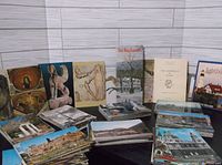 Wide view of stacked and spread vintage postcards showing a variety of scenes including architecture, statues, and cityscapes from various locations.