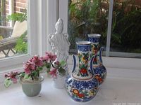 View of two Asian style vases, white figurine, and potted jade plant on windowsill