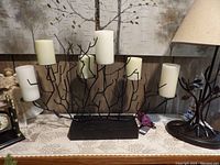 Black metal branch-shaped candelabra with five attached battery operated candles.