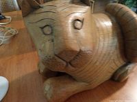 Close up front view of the carved wooden cat face and upper body showing detailing in carving and painted facial features.