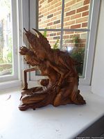 Front view of the wooden sculpture showing the couple in intimate embrace with detailed headdresses and traditional dress.