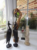 Photo showing entire group of handcrafted decorative sculptures including wooden birds, metal figurine, and stone candle stick holder