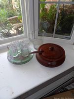 Glass pitcher, wooden lidded bowl with spoon, and four glass mugs on a matching plate with grapevine and leaf design in green and purple