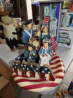 Hand-painted Americana patriotic figurine centerpiece with four figures in colonial attire and a large USA striped base