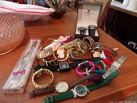 Top view of assortment of wristwatches and watch bands displayed on wooden surface