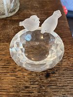 Top and angled views showing details of the clear faceted glass dish with two frosted glass birds perched on the edge.