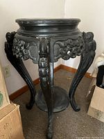 Front view of tall dark wood antique table with detailed carvings on legs and decorative panels