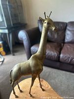 Brass giraffe statue shown with clear details of head, neck, body, and legs.