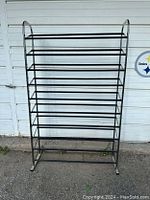 Full front view of the black metal shoe rack showing 8 shelves and rounded top frame