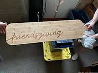 Wooden serving board showing full front view with 'friendsgiving' scripted etching visible along the length.