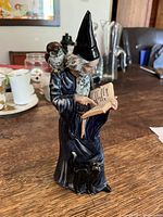Front view of Royal Doulton The Wizard figurine showing the wizard, owl on shoulder, and black cat at base.