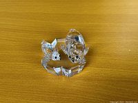 Two clear Swarovski crystal seal figurines with faceted surfaces and black eyes placed on a wooden surface.