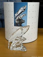 Clear Swarovski crystal Wales figurine with blue eyes, shown with original box. Figurine has polished, smooth glass and detailed wave design.