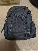 Front view of the black Tenba camera bag showing mesh front pocket with drawstring and side mesh pockets.
