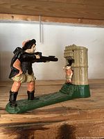 Side view of the painted cast iron bank with soldier aiming gun and piggy in castle tower.