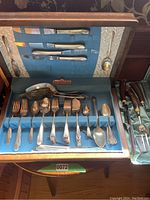 Full view of 1847 Rogers Bros vintage silver plated carving set and assorted flatware in original case with blue felt and patterned interior.