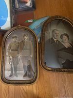 Two long oval and oval antique brass frames showing vintage photos of men in military uniform and a couple in period attire.