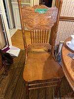 Front view of one oak pressback chair showing contoured seat, turned legs and spindles