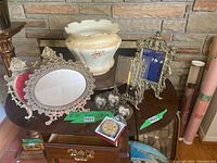 Wide view showing the entire lot on a wooden table including the porcelain planter, large oval frame, dual oval frame, heart-shaped frames, and other small decorative items.