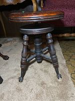 Side view showing adjustable height mechanism and claw feet with casters on an antique Victorian piano stool.