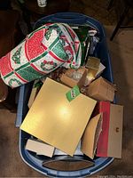 Blue plastic tub containing various Christmas decorative boxes and wrapped items