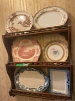 Six decorative plates on an oak hanging rack showing varied designs and colors