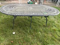 Full view of oval cast aluminum table on grass