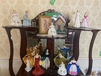 Overall view of ten porcelain figurines displayed on wooden hall table with mirror