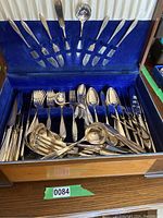 Full view of the silver cutlery set inside a blue velvet-lined wooden box, showing multiple forks, spoons, knives, and serving pieces.