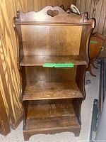 Front view of the wooden bookcase showing three shelves and the small heart carved detail at the top.