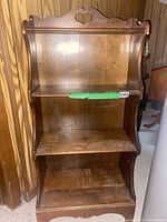 Front view of wood carved bookcase showing three shelves and heart cutout on top back panel.