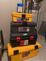 Stack of four tool boxes in yellow, black, and grey colors with labels from Mastercraft, RubiMate, Rubbermaid brands.