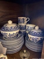 Stack of dinner plates, side plates, and two lidded sugar bowls in Blue Willow pattern