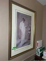 Framed vintage wall art hanging on the wall, showing full artwork and frame.