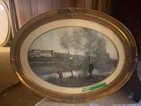 Full image of oval vintage framed art piece showing the landscape, gold ornate frame, and beige matting.