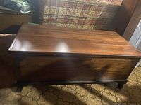 View of the front and top of the wood chest showing polished wood grain and rectangular construction.