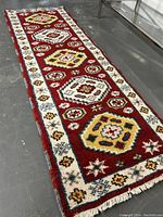 Full length view of the Nahavand wool runner rug placed on a gray floor showing border and central motifs with fringed ends.