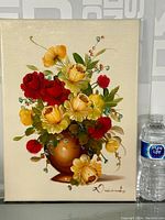 Full view of the floral bouquet oil on canvas painting next to a water bottle for scale, showing signature on lower right.