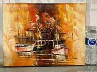 Full view of signed oil painting on canvas depicting boats docked at a pier with wooden buildings in the background, showing overall condition and color.