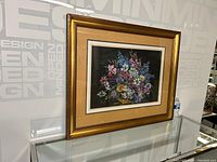 Full view of framed floral pastel painting on black background with floral bouquet in gold bowl
