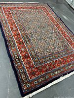 Full view of rectangular carpet laid on floor showing overall design, borders, field and fringe