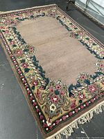 Full view of the rectangular Savoineri handmade wool rug with floral border and fringe lying flat on floor.