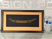 Full view of the framed print showing the Haida canoe design with a water bottle for size reference.