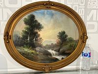 Wide view of the oval framed watercolour painting showing the natural landscape scene with water, trees, and hills.