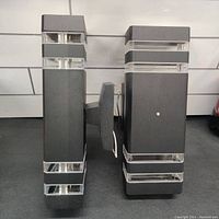 Two identical black rectangular outdoor wall light fixtures side by side, showing front and side views.